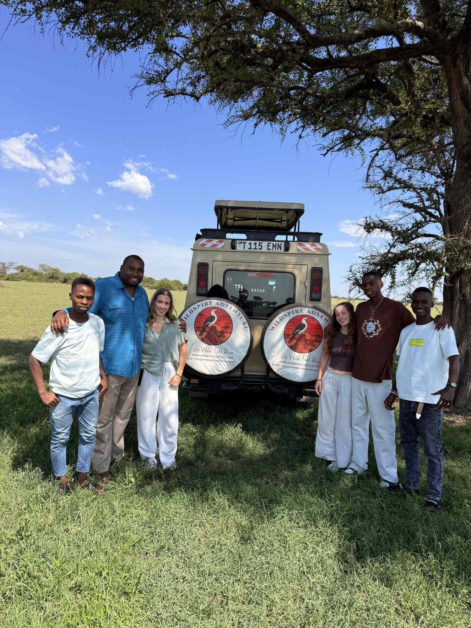 Wildspire travellers with their Tanzanian guides beside the safari vehicle